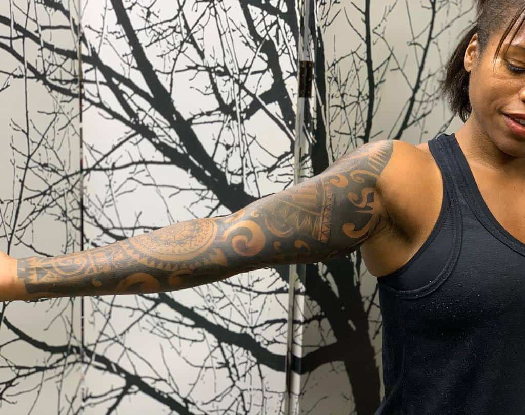 Bold full-sleeve tribal tattoo with intricate geometric and swirling patterns, extending from shoulder to wrist