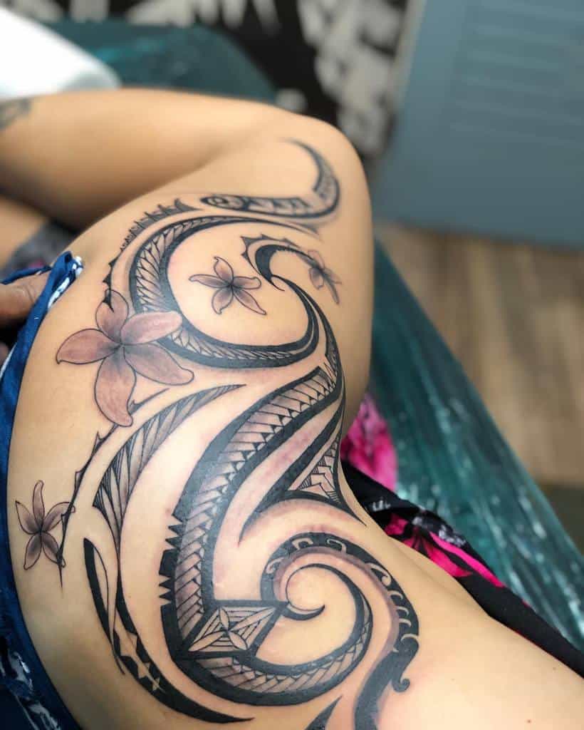Tribal hip tattoo with bold swirling patterns and delicate floral accents, extending across the side of the body