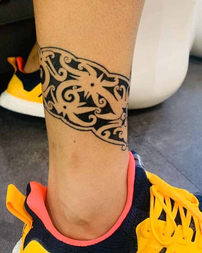 Leg with bold tribal armband tattoo above an ankle