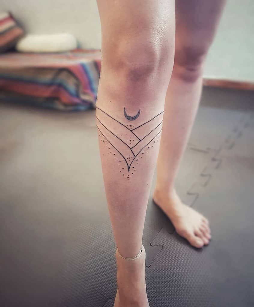 Leg tattoo with a crescent moon, geometric lines, and dot patterns on a woman's lower leg