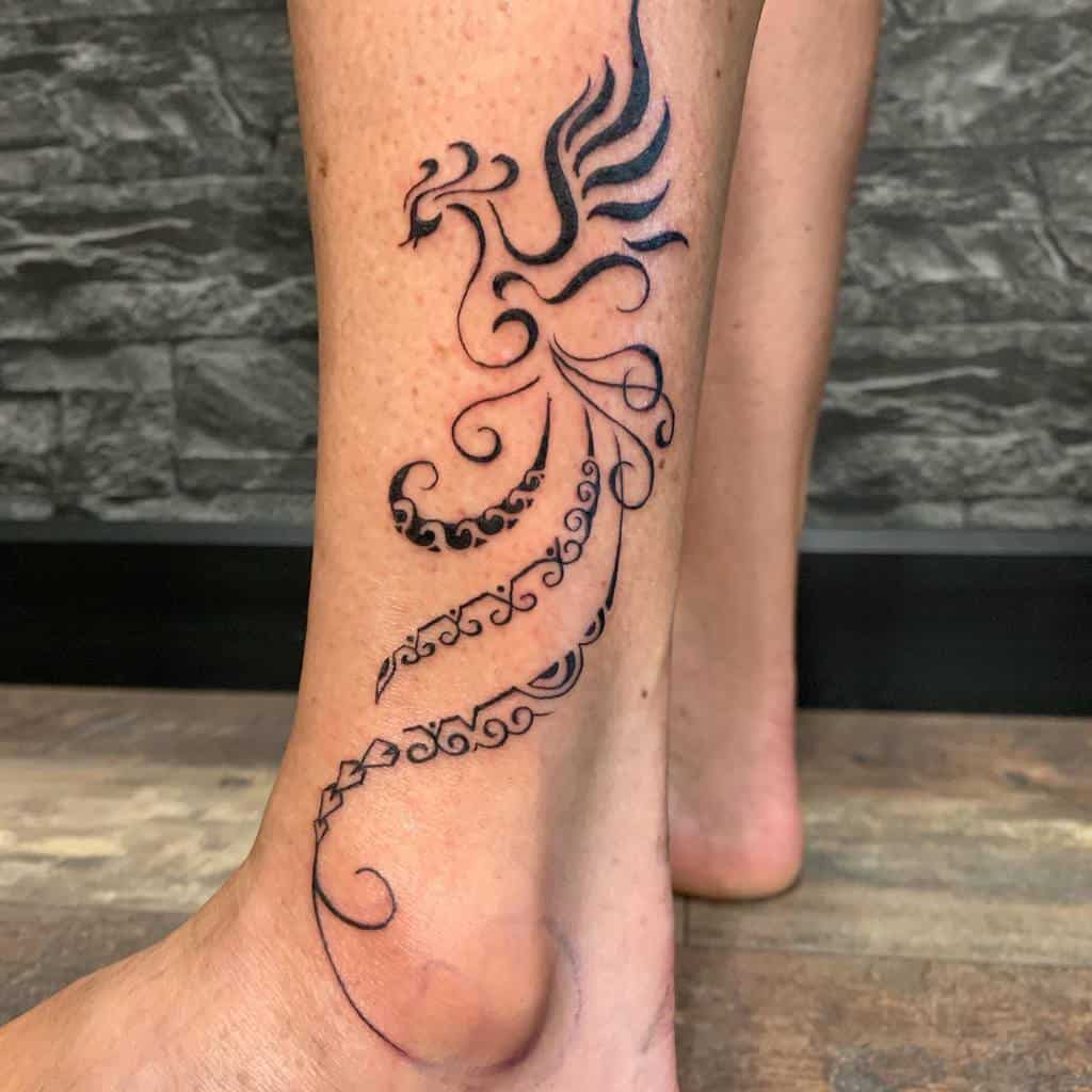 A tattoo of a stylized phoenix with intricate tribal details on a leg