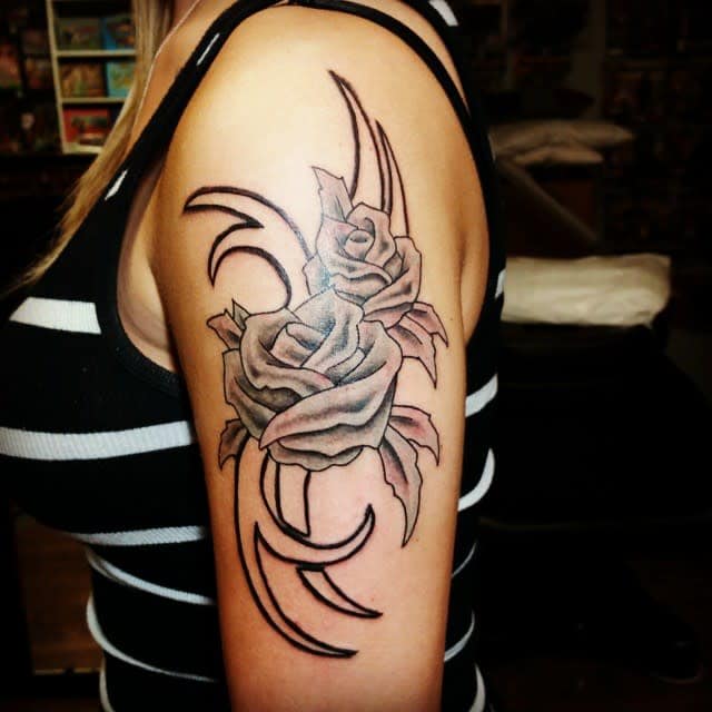 Tattoo of a rose with abstract black lines on an upper arm