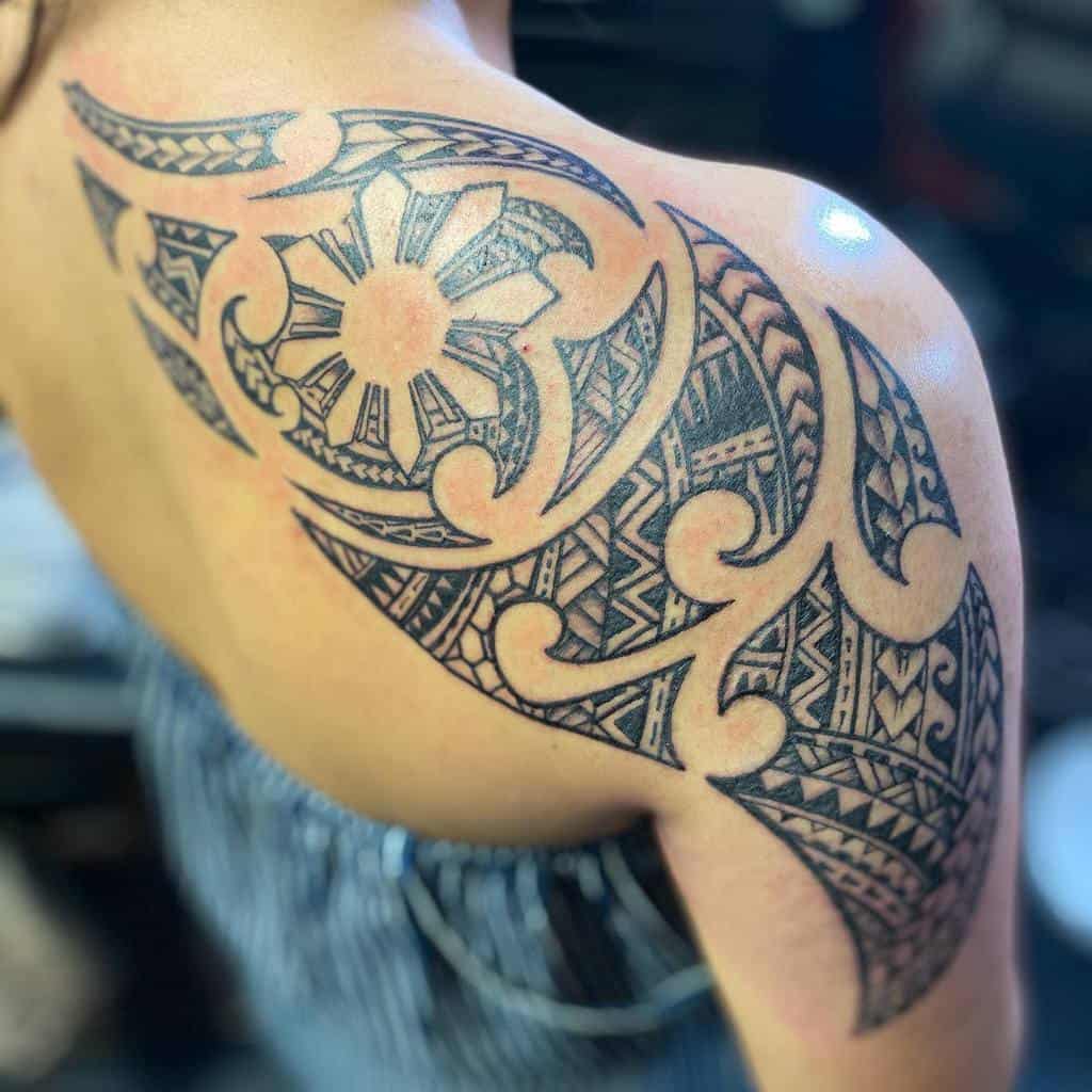 Arm tattoo with intricate Polynesian tribal patterns and a sun motif on the shoulder