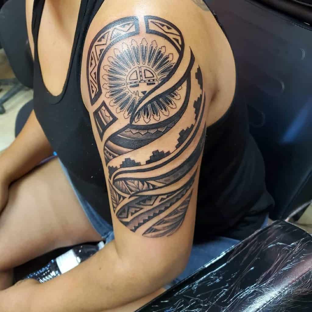 Tribal-style tattoo on the upper arm, featuring circular and geometric patterns in black ink