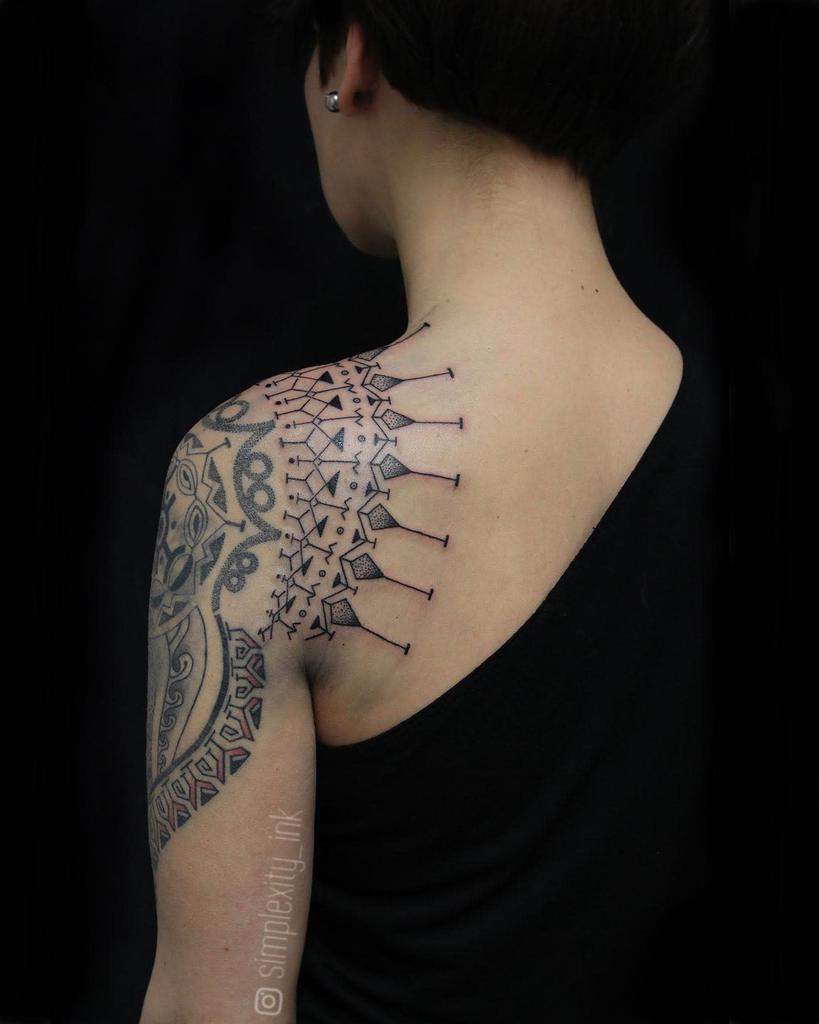 Person with geometric and tribal tattoos on shoulder and upper arm