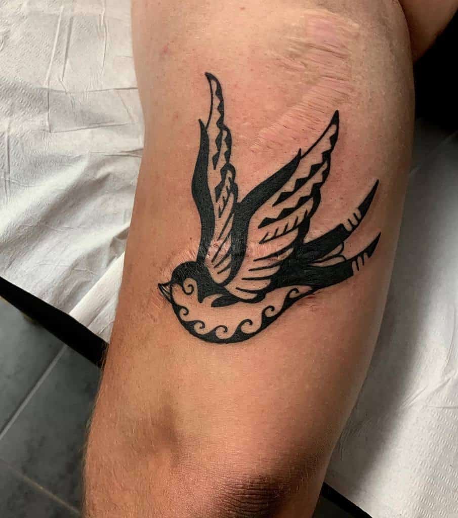 Tattoo of a black bird with outstretched wings on an arm