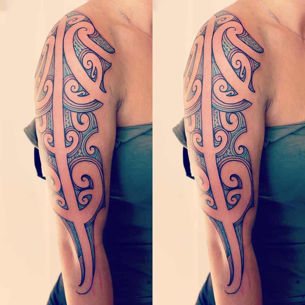 Arm tattoo with intricate tribal design in blue and black ink