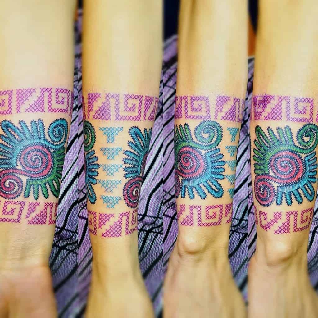 Cross-stitch tattoo armband with intricate geometric and spiral patterns in vibrant pink, blue, and green