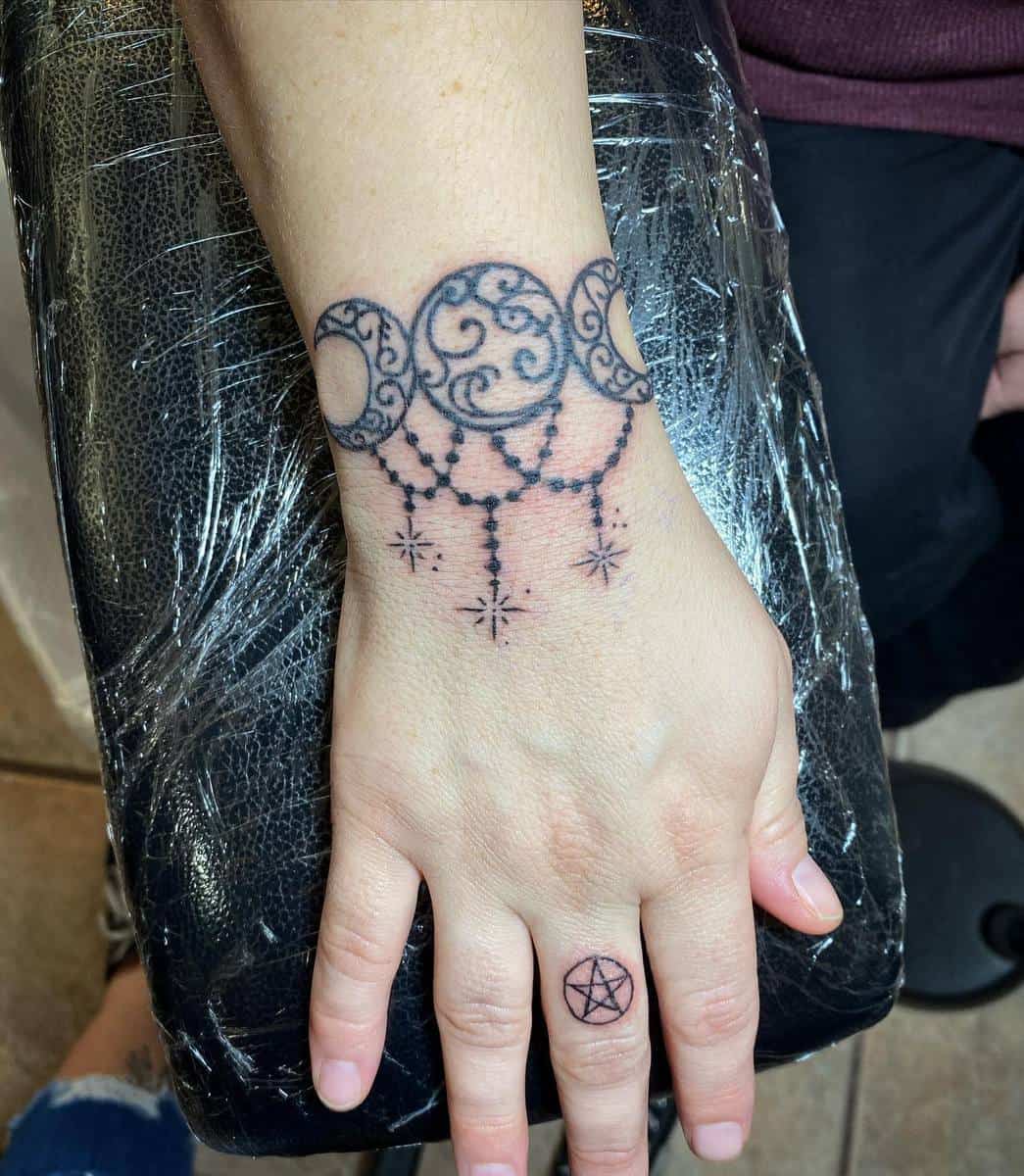 Ornamental moon phases and stars tattoo on wrist with a pentacle symbol on finger