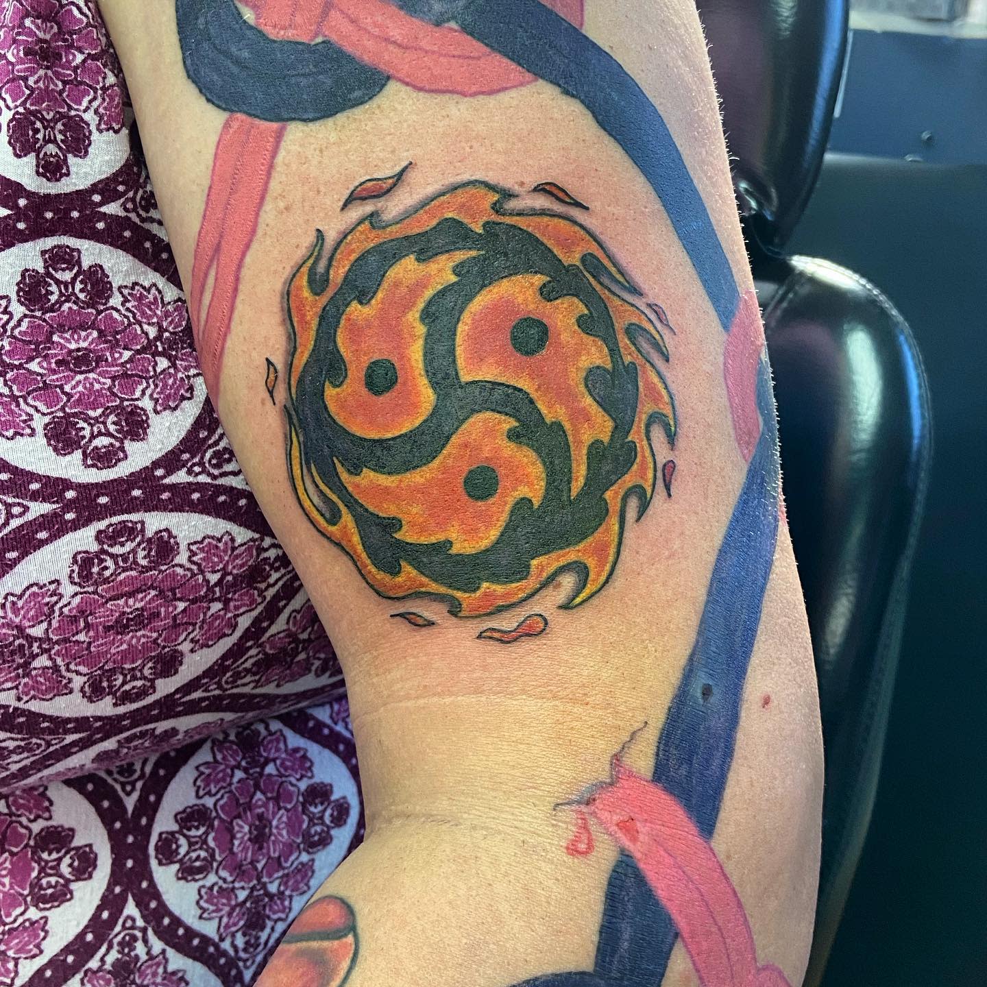 Triskelion forearm tattoo surrounded by flames