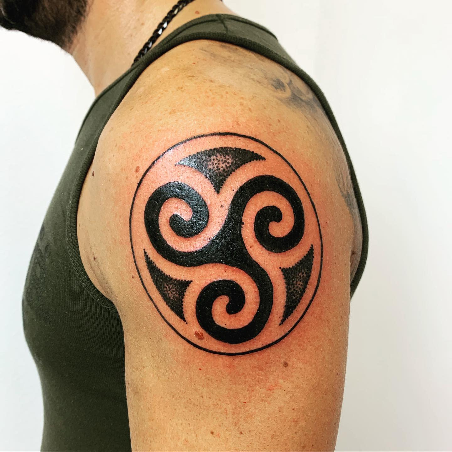 Person with a black triskelion tattoo on the upper arm