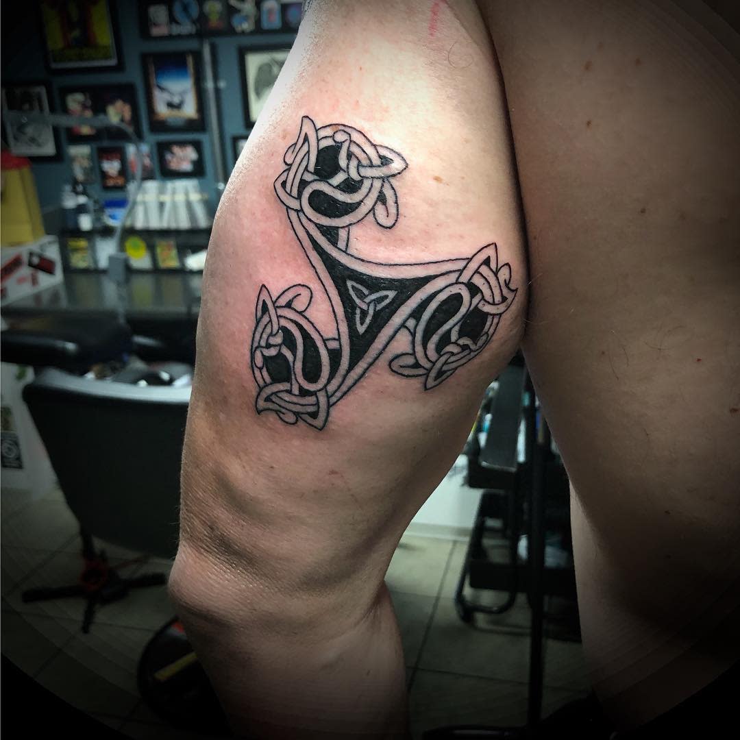 Upper arm tattoo featuring a Celtic Triskelion with knotwork, symbolizing strength and eternity