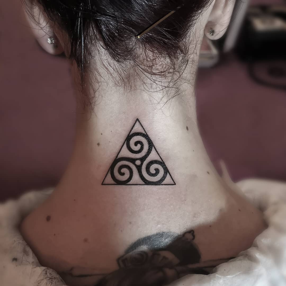 Back of neck tattoo of a Triskelion within a triangle, representing harmony, balance, and protection