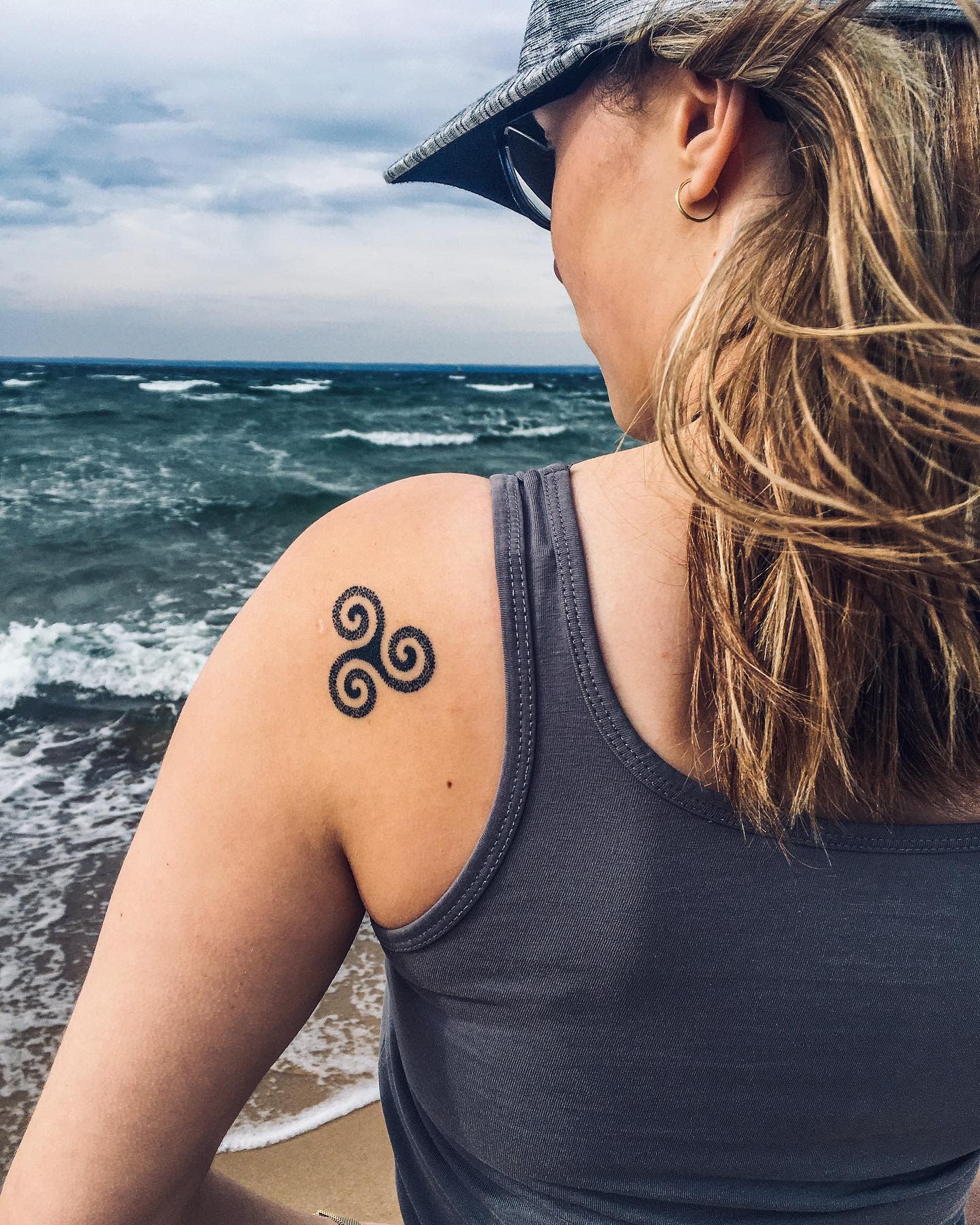 Shoulder tattoo of a minimalist Triskelion, symbolizing movement and connection with nature
