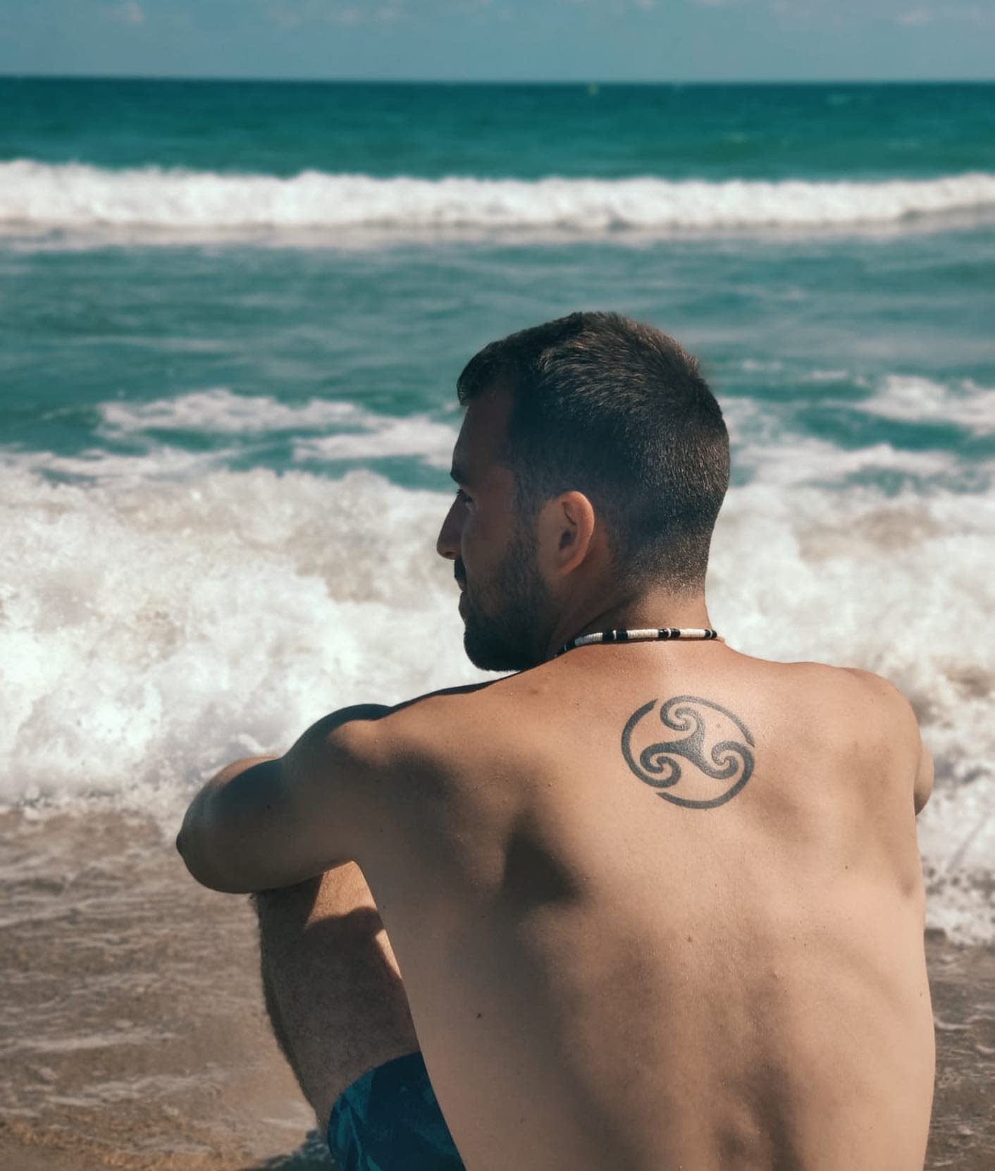 Back tattoo of a Triskelion, symbolizing life’s cycles