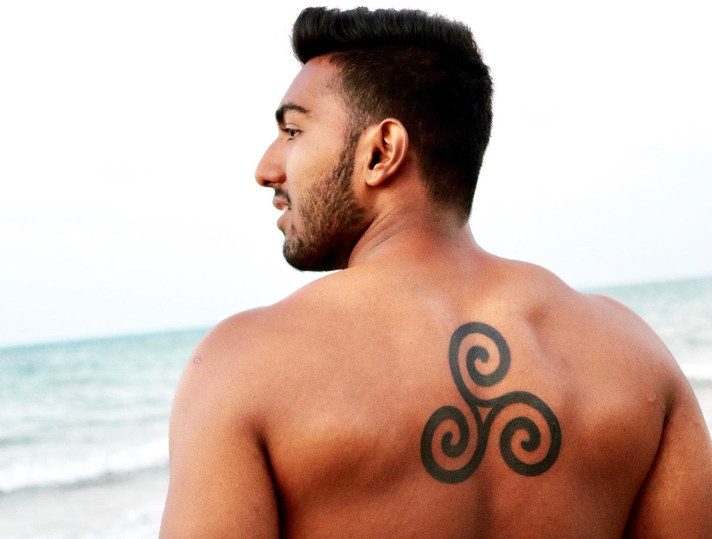 Large back tattoo of a bold Triskelion, symbolizing strength, balance, and life’s cycles