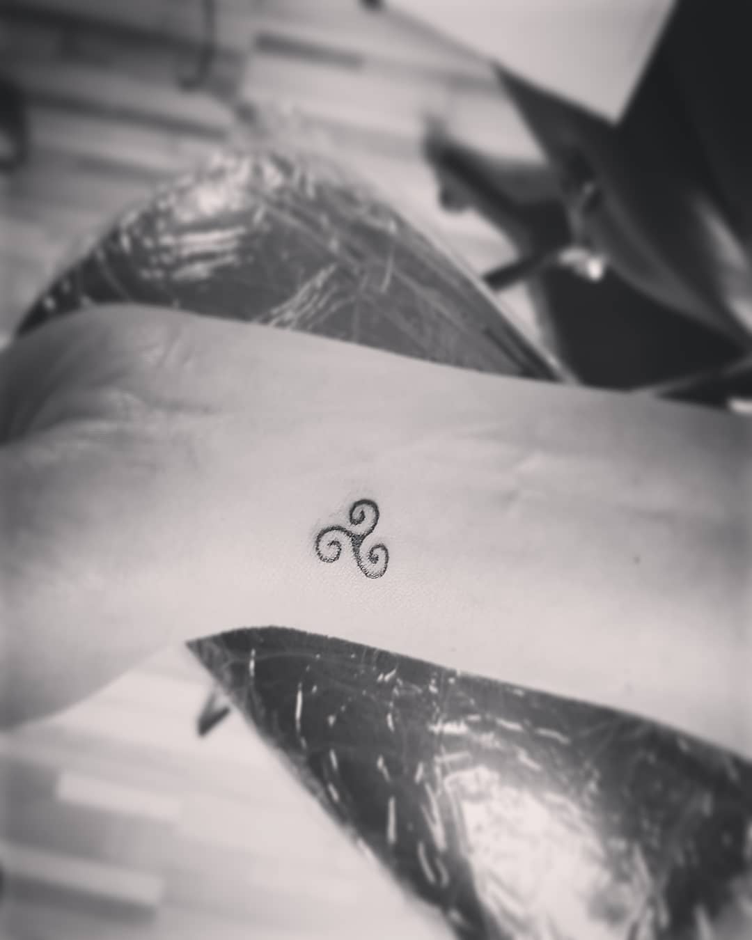 A small triskelion tattoo on a wrist