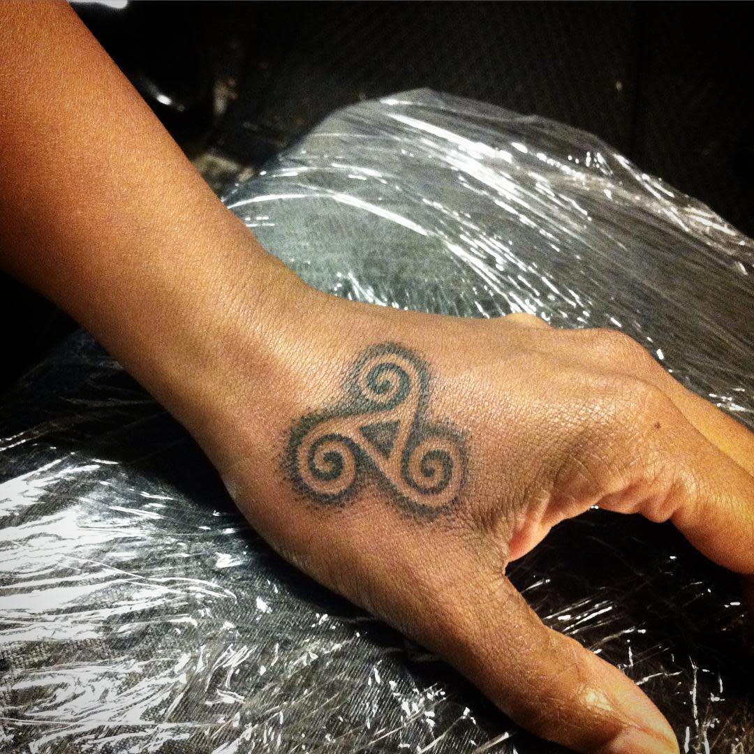 A small triskelion tattoo on the back of a hand
