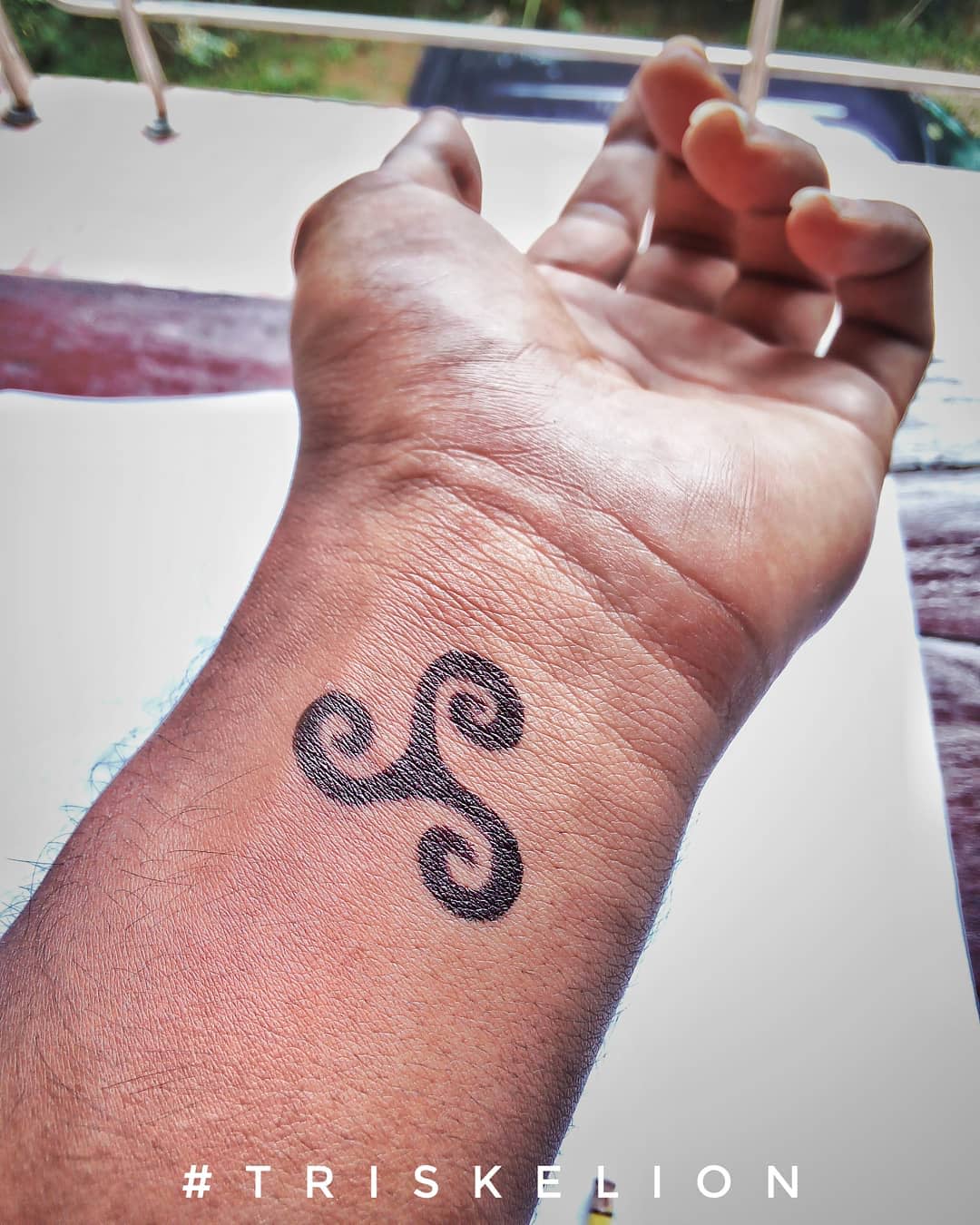 A wrist tattoo showcasing a triskelion symbol