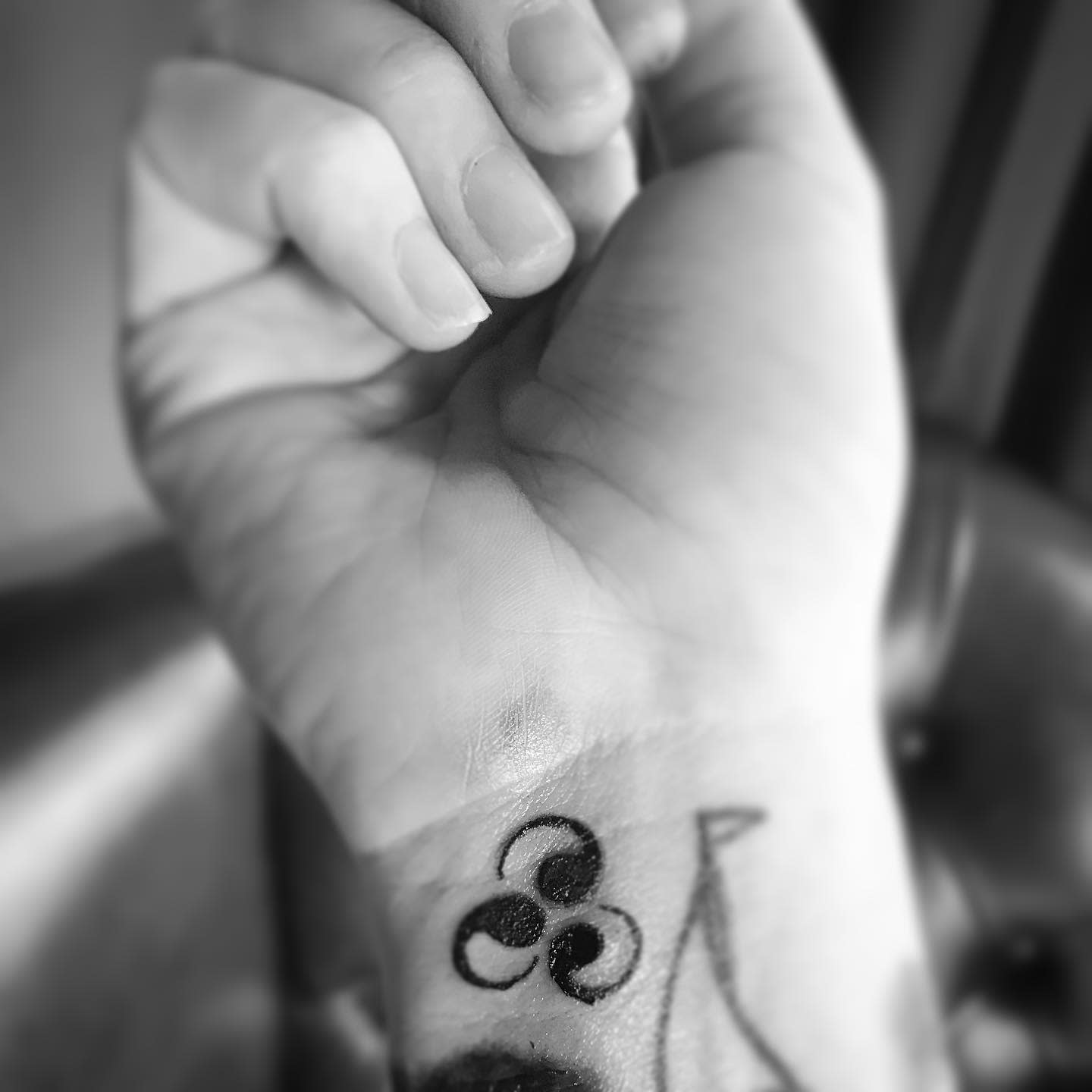 Black triskelion tattoo on a wrist
