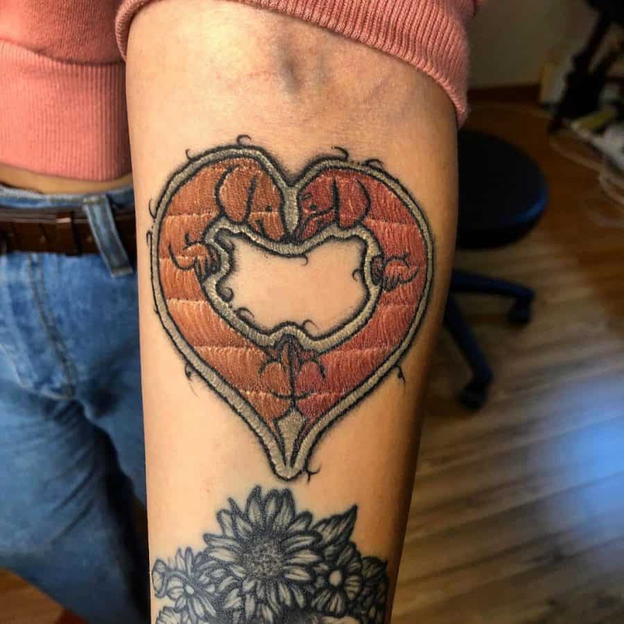 Decorative embroidery-style tattoo of a heart with intricate thread-like textures, blending fabric-inspired art with classic motifs.