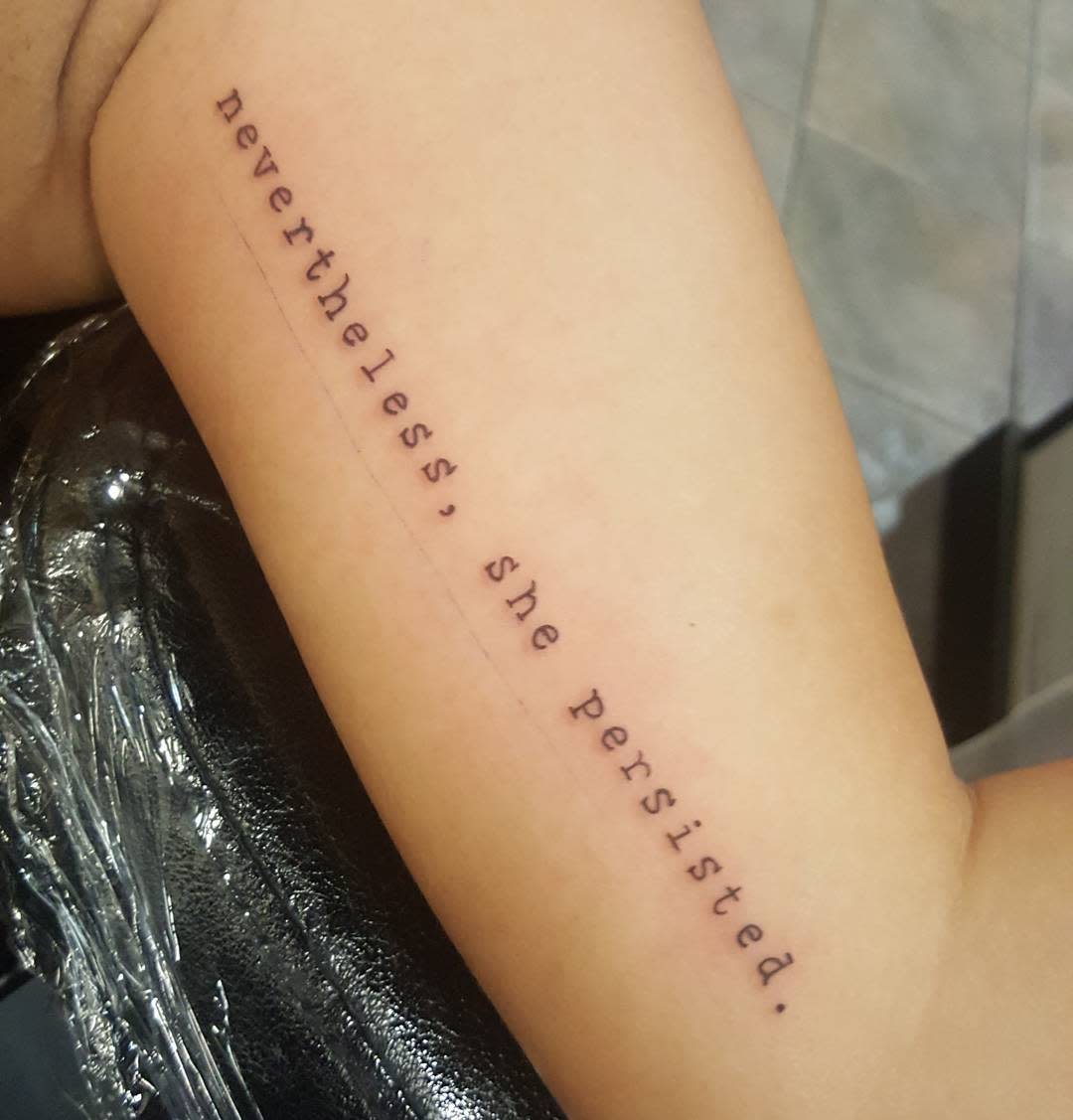 Text tattoo on forearm reading "nevertheless, she persisted"