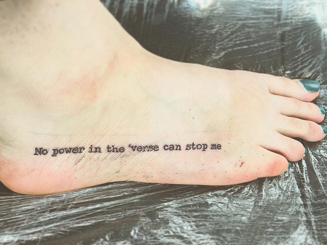 Foot tattoo reading "No power in the 'verse can stop me" in black ink