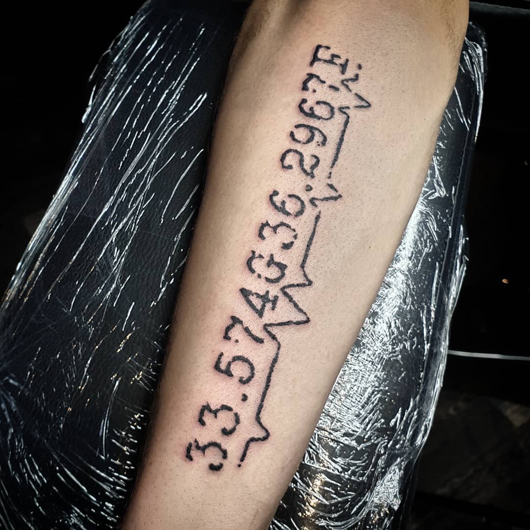 Tattoo of coordinates and a heartbeat line on an arm
