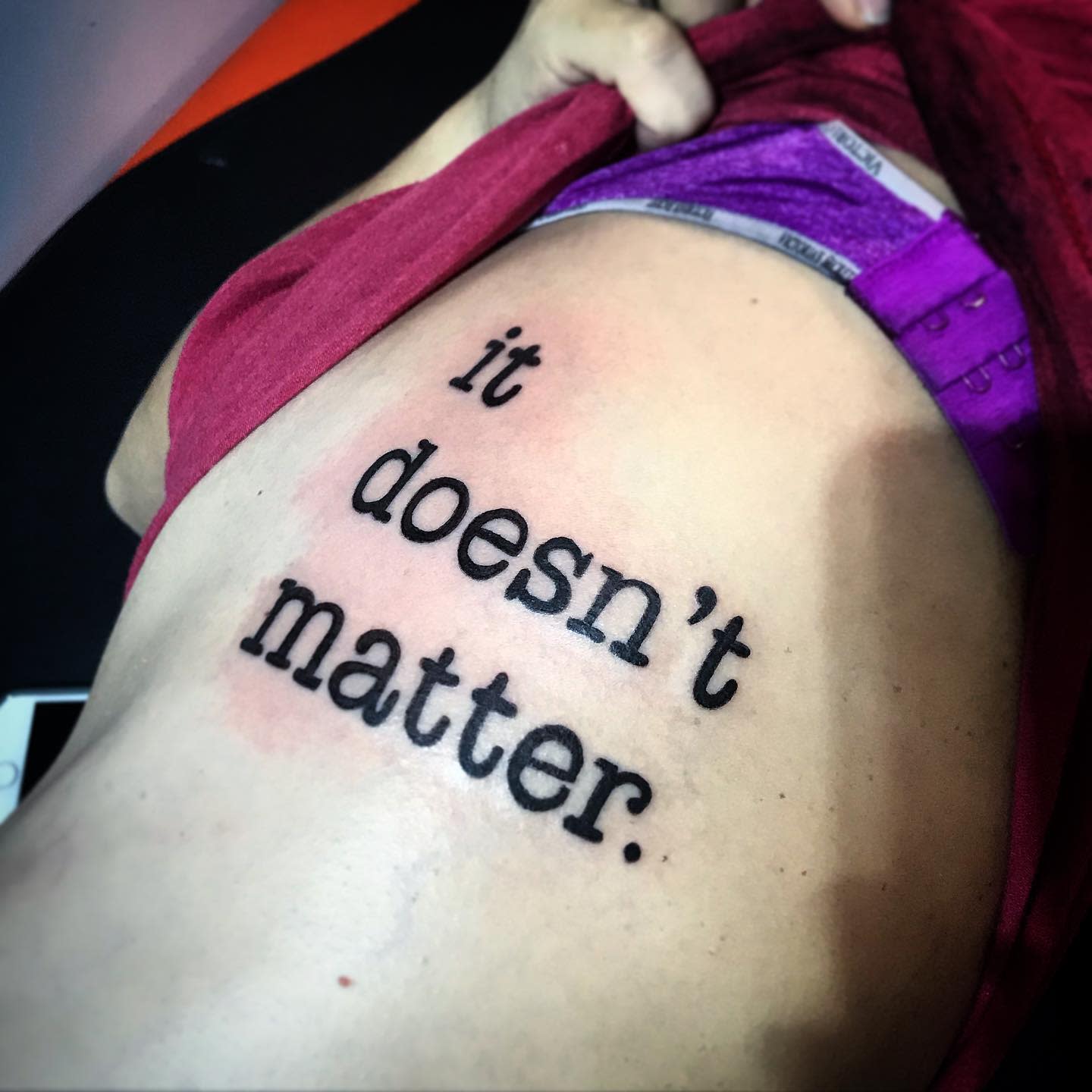 Tattoo of the phrase "it doesn't matter" on side torso