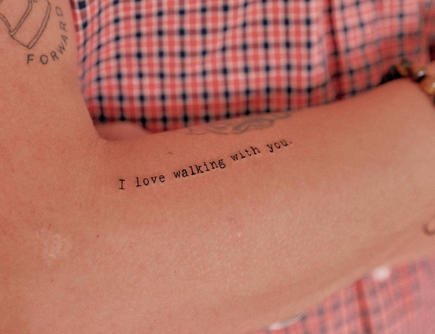Close-up of an arm tattoo reading "I love walking with you" 