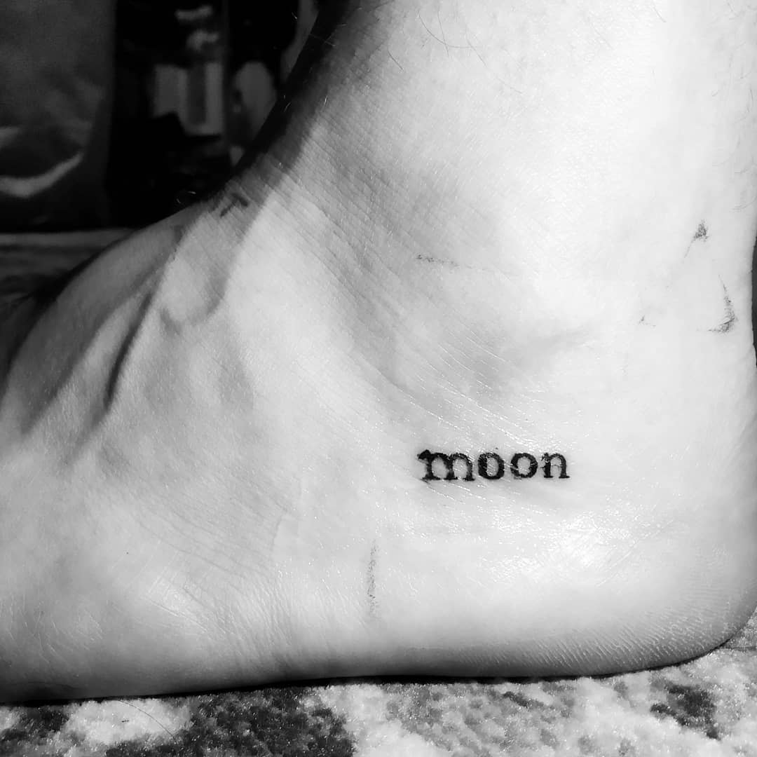 A tattoo of the word "moon" on the inside of a foot