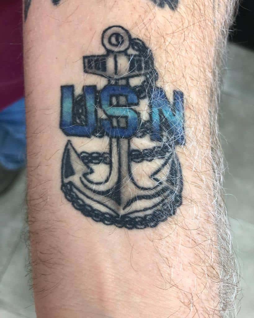 Tattoo on a forearm featuring the letters "USN" above a navy anchor