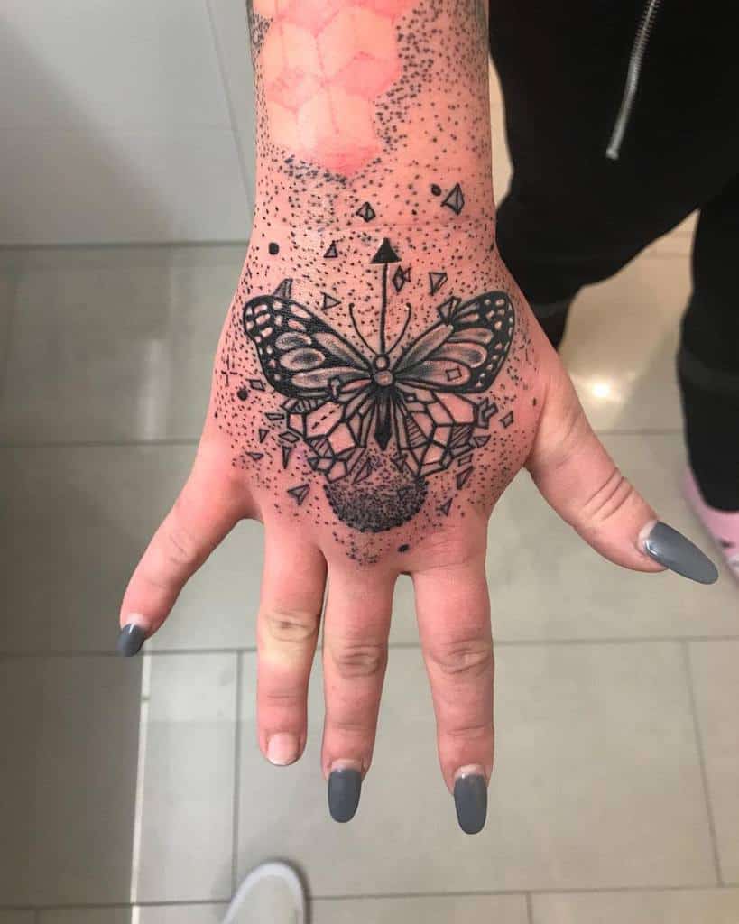 Hand tattoo with a detailed butterfly design and geometric shapes around it