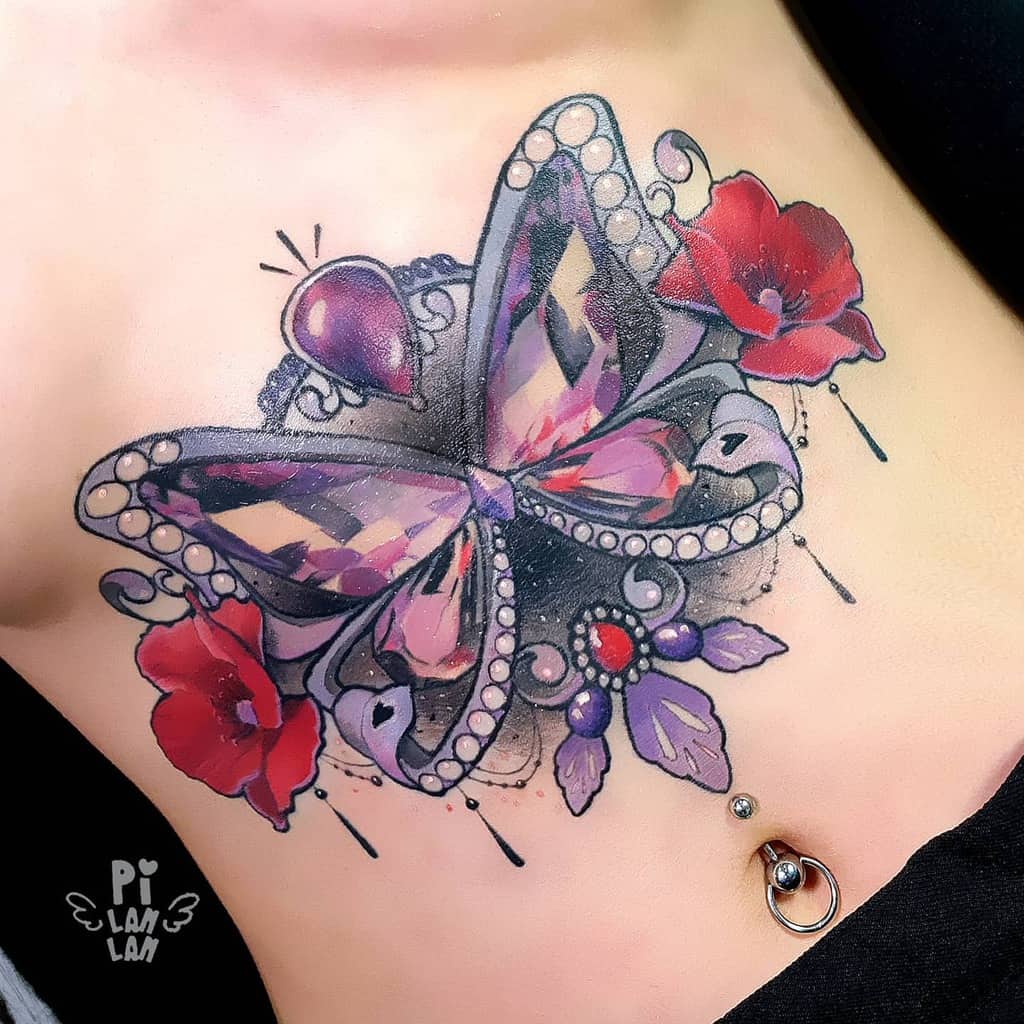 Tattoo of a jeweled butterfly with red flowers and intricate details on someone's chest