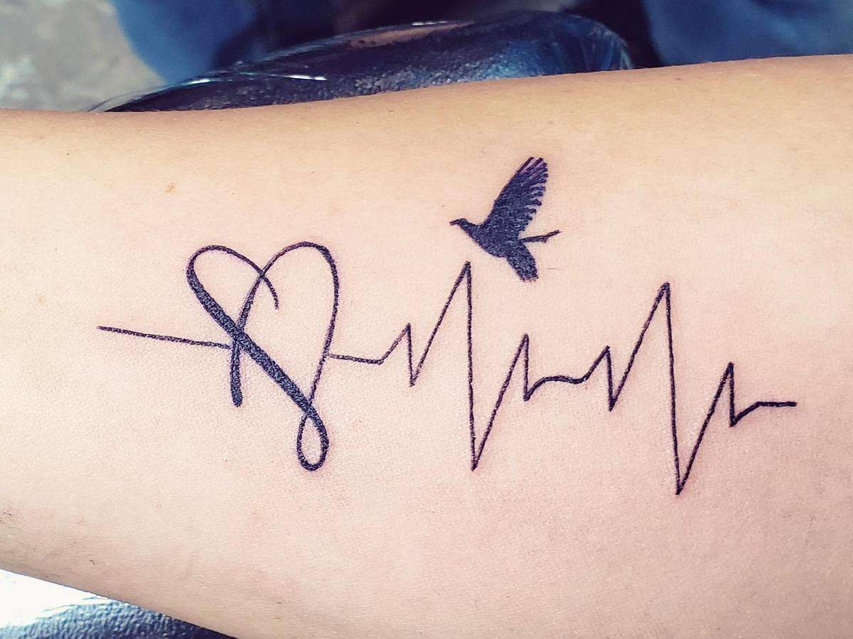 Tattoo of a heartbeat line with a heart and a flying bird