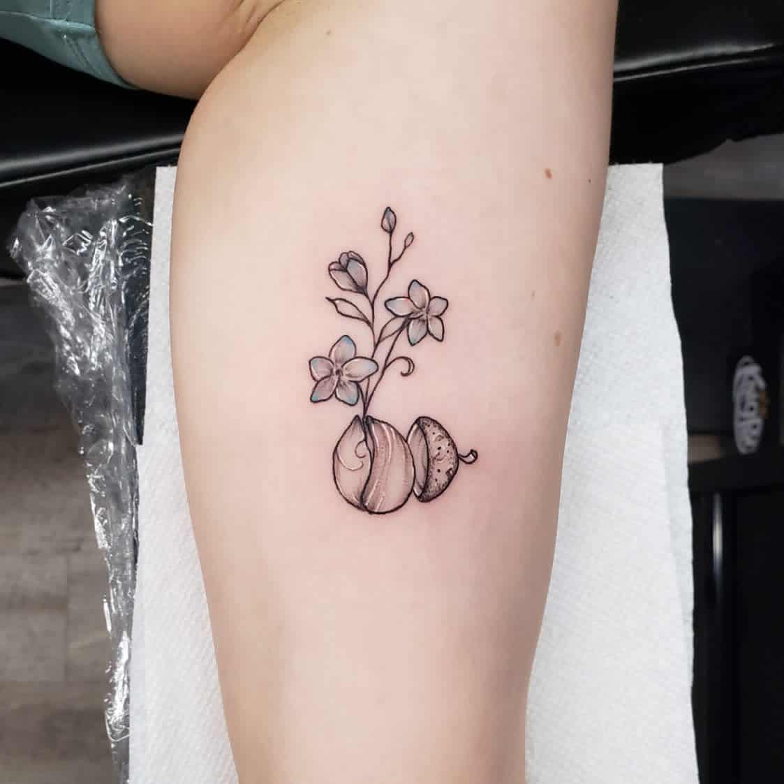 Tattoo of blooming flowers sprouting from cracked eggshells located on the inner arm