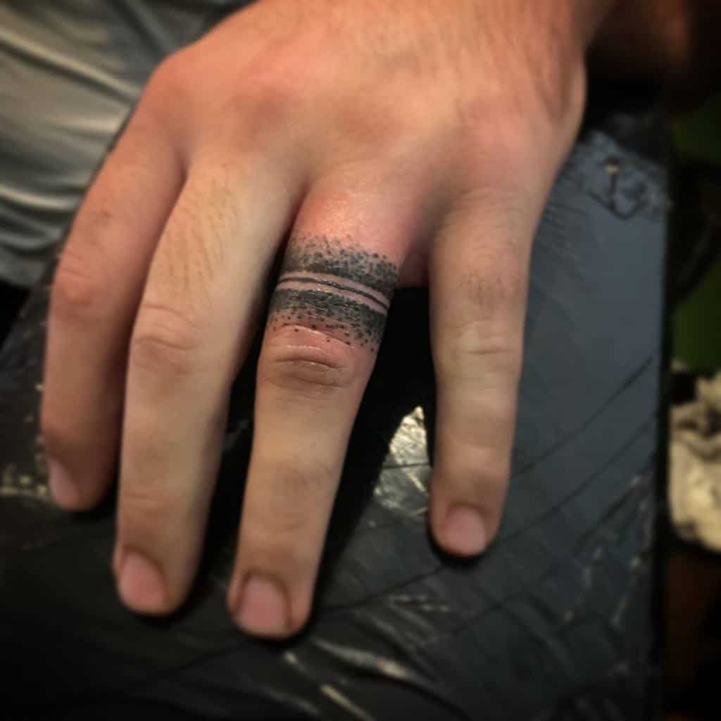 A ring tattoo of black dots and lines on the finger