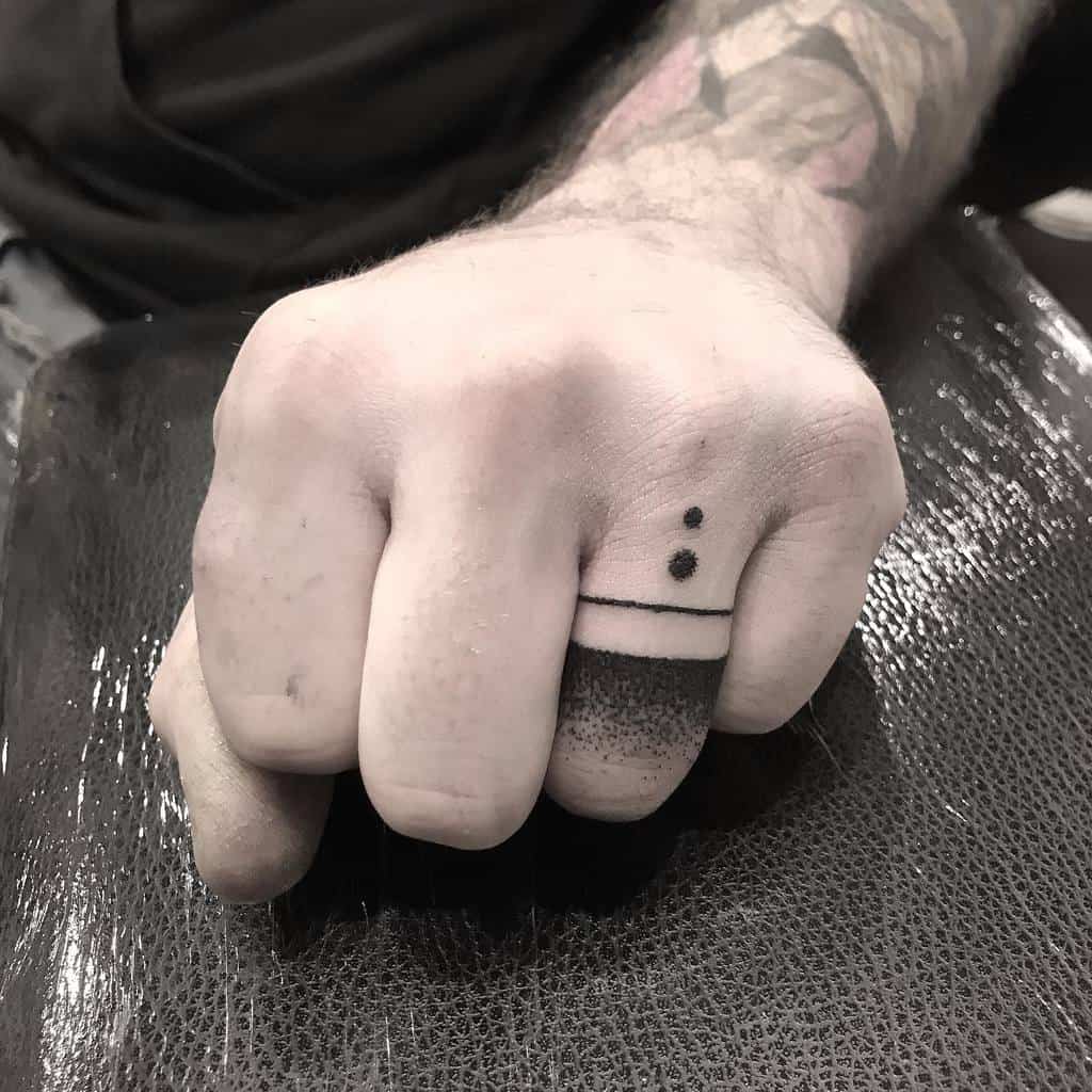 A blackwork ring tattoo, featuring two dots above a thick, solid black band