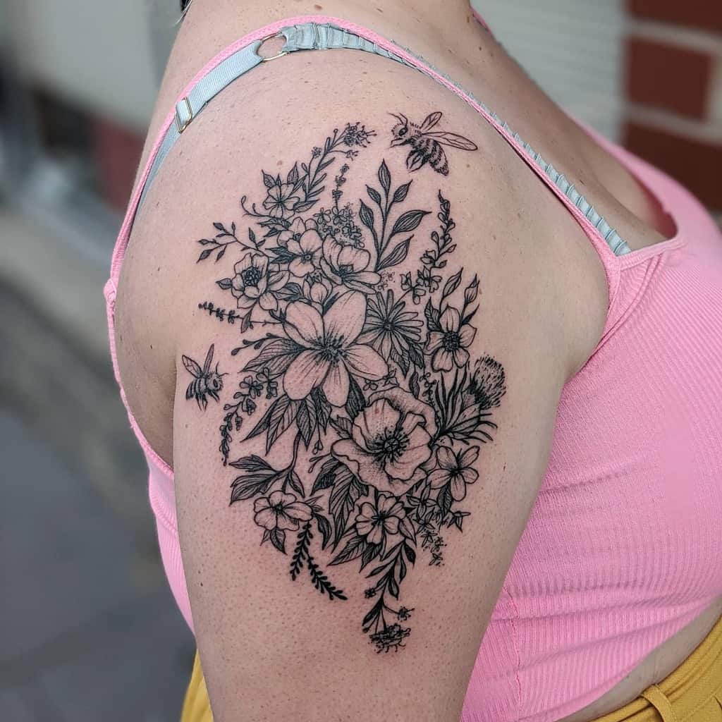 Floral tattoo with bees and dragonfly on woman's upper arm