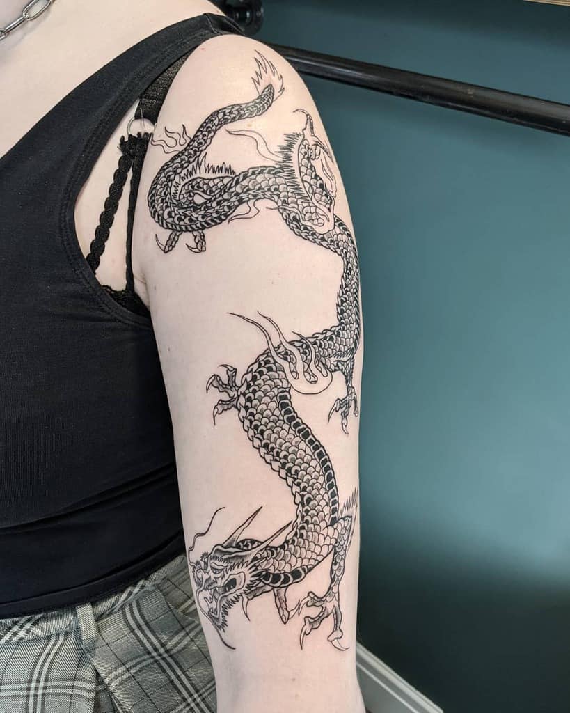A detailed black dragon tattoo wraps around an upper arm