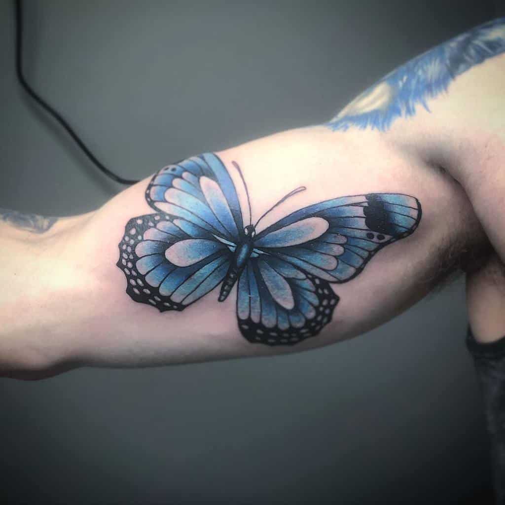 Tattoo of a stunning blue butterfly with intricate black accents on an upper arm