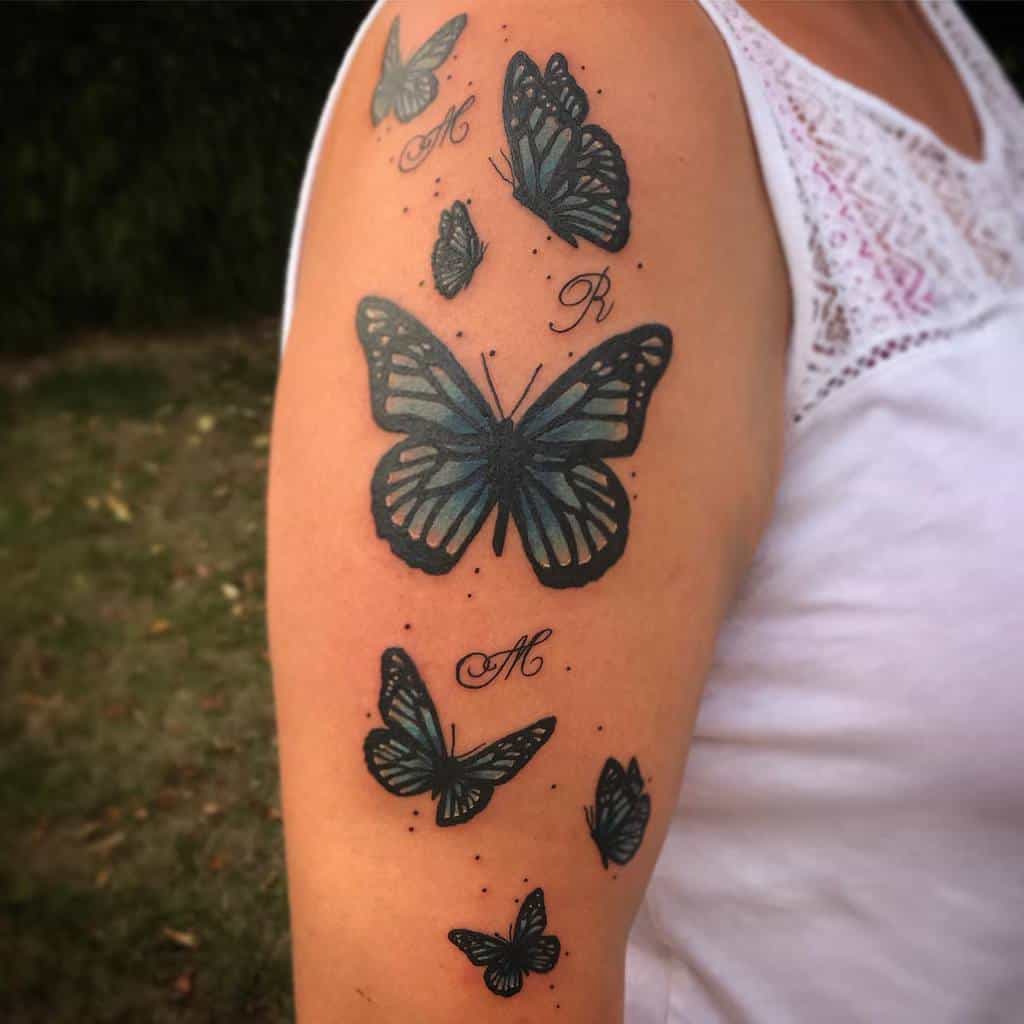 Person's arm with black and grey butterfly tattoos, including a vibrant blue butterfly, and initials "M" and "R" next to some butterflies