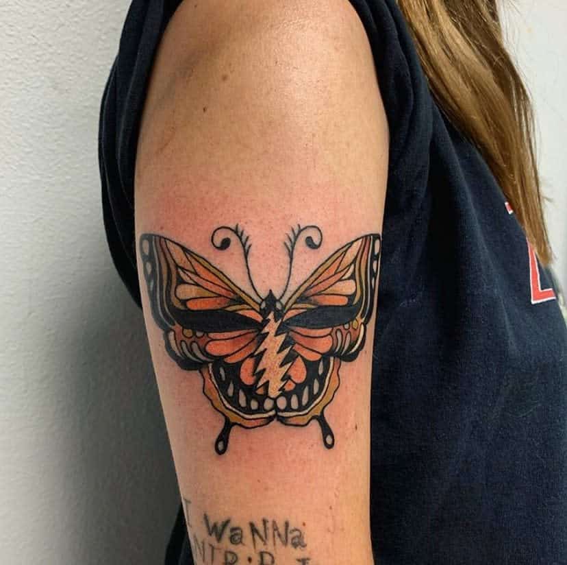 A colorful butterfly tattoo on a person's upper arm