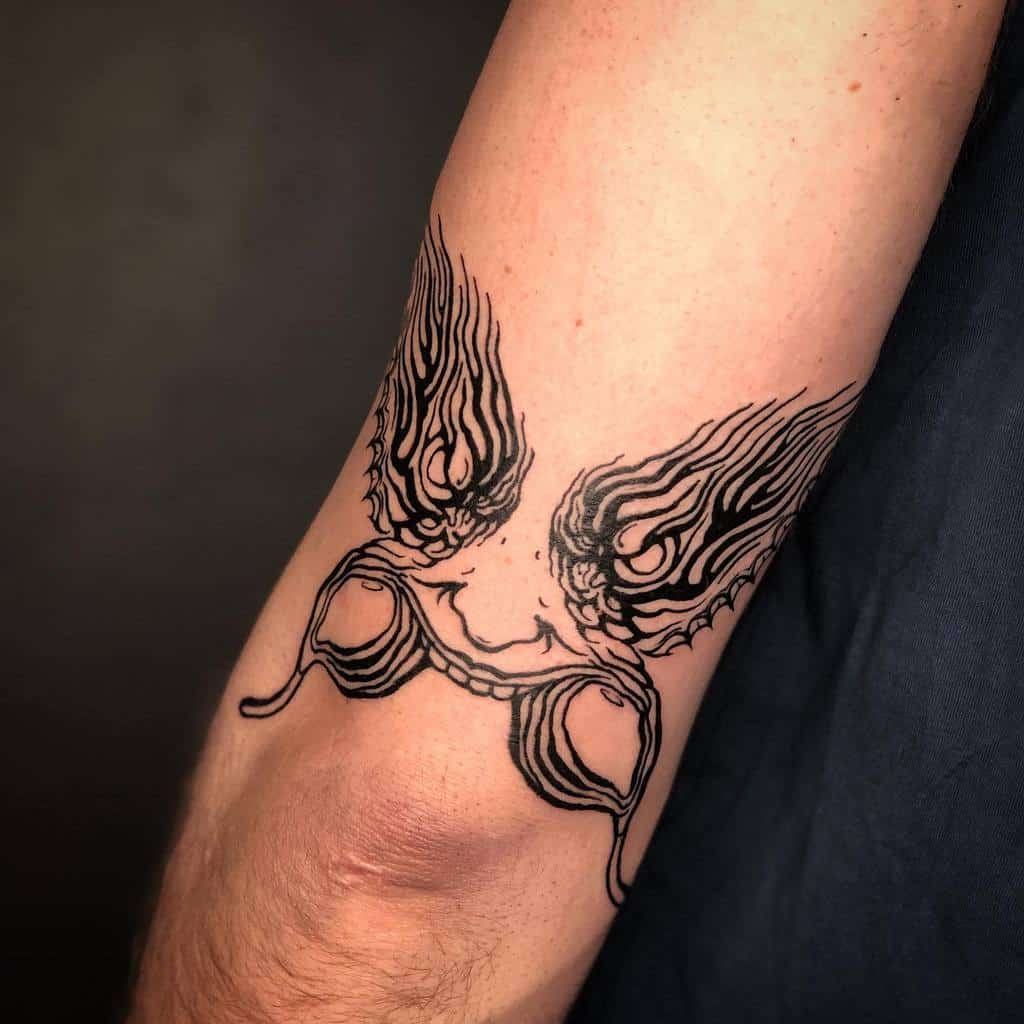 Tattoo of winged spectacles on an arm, with intricate line details over a background of skin