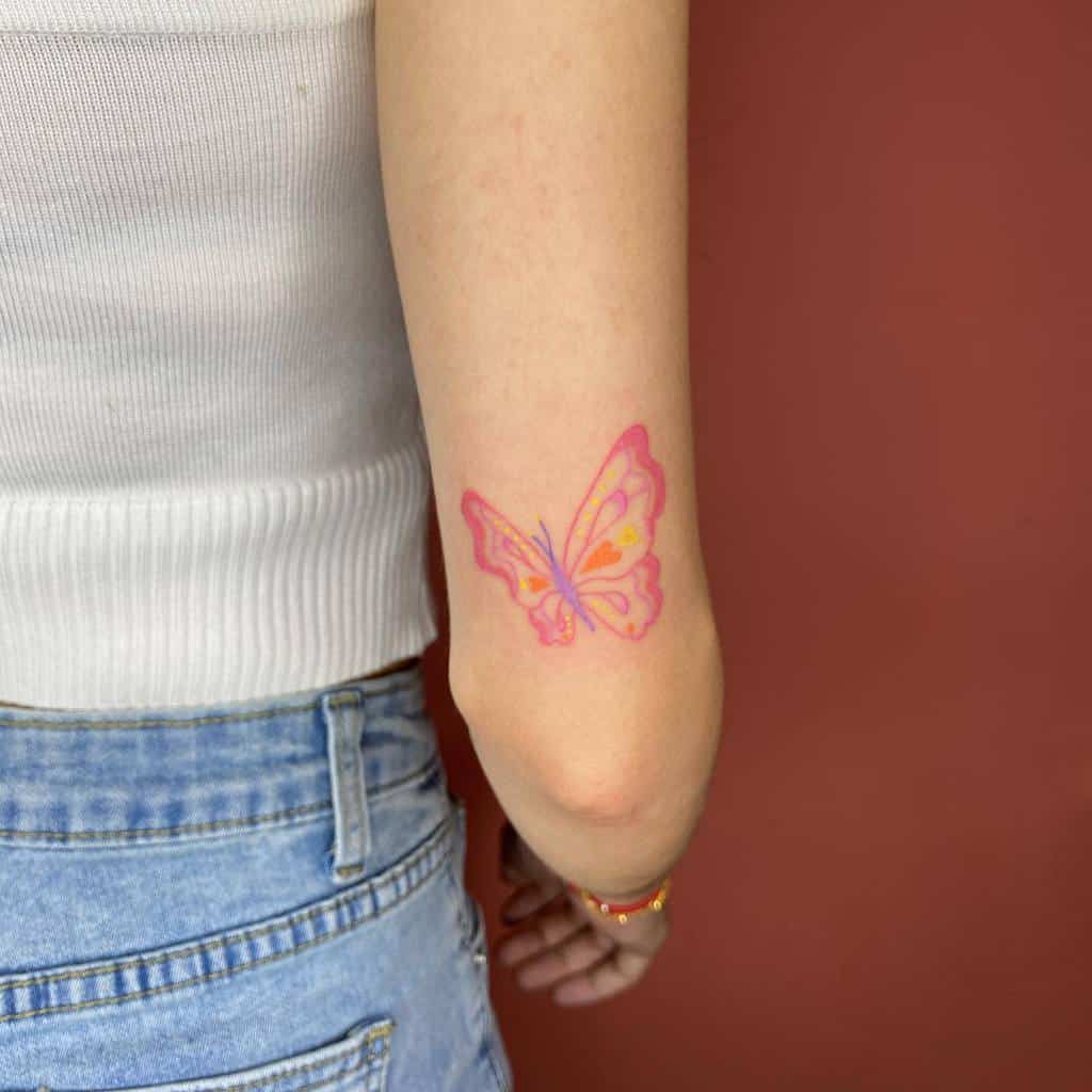 A person with a pink butterfly tattoo on their arm