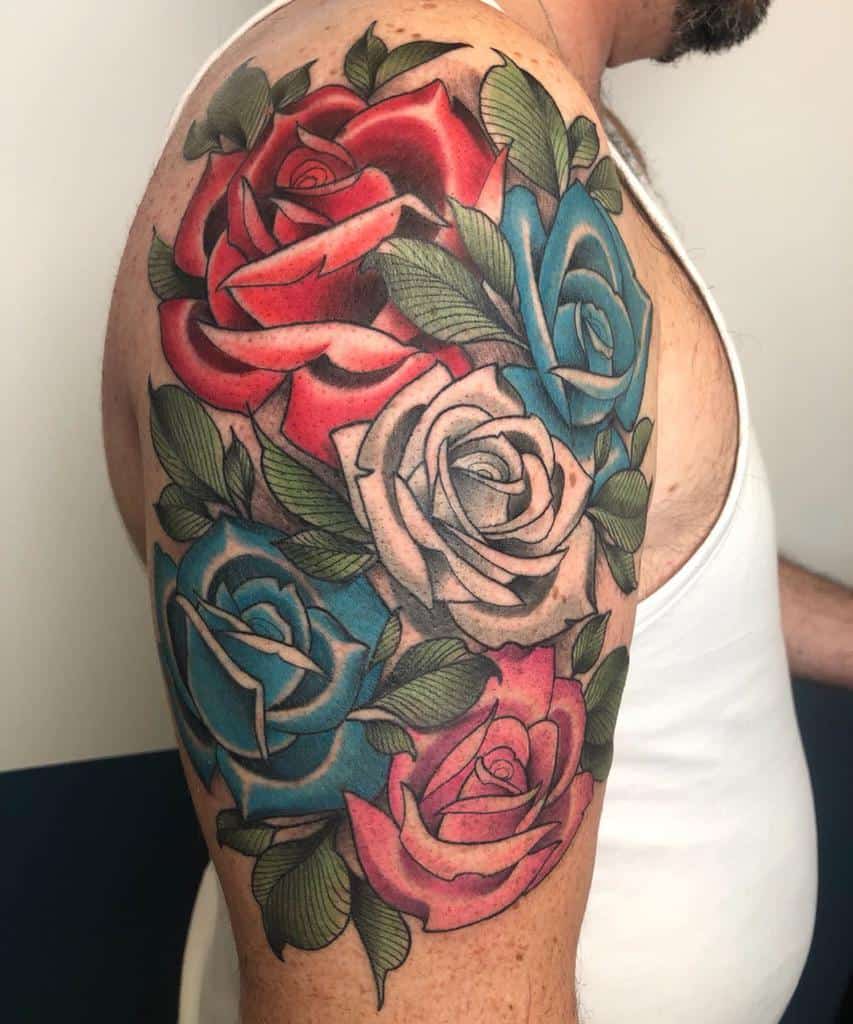 A stunning sleeve tattoo featuring vibrant red, blue, and pink roses entwined with lush green leaves