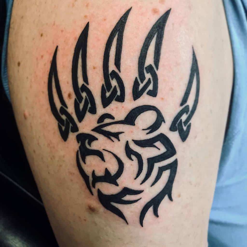 A tattoo of a stylized bear head, accentuated with fierce claw marks in black ink