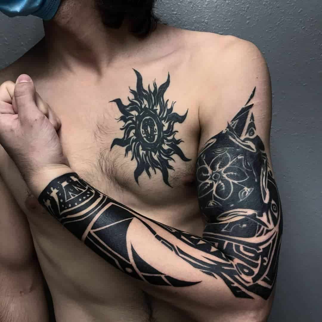 A detailed black and grey tattoo featuring Uta's sun design on the chest and intricate abstract patterns on the arm, creating a cohesive and striking look