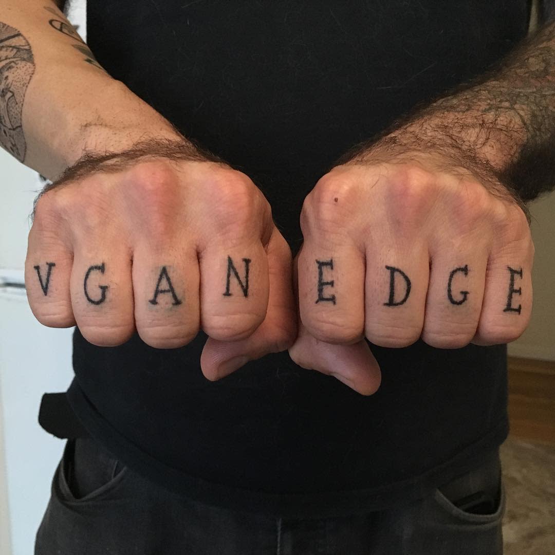 Two fists with straight edge tattoos spelling "VGAN EDGE" in black ink