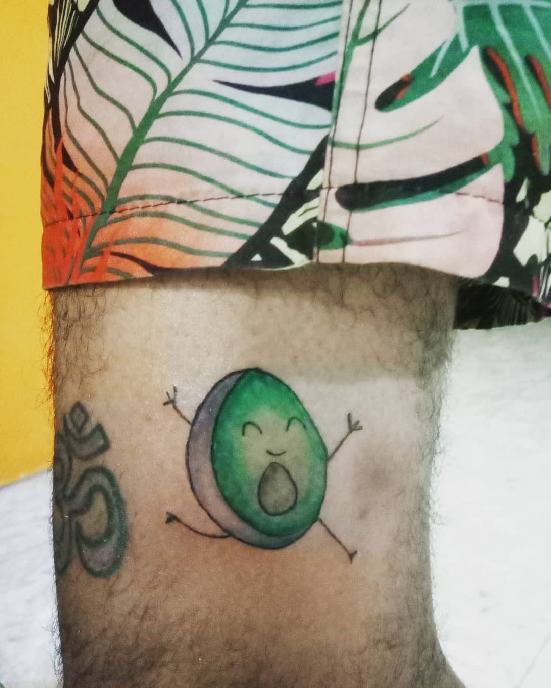 Tattoo of a running avocado on a leg